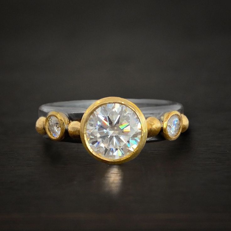 - Sterling Silver, 18k Gold - Charles & Colvard Hearts & Arrows Moissanites - Choice of center stone size: .5, 1.25 - Side stones equal .25 carats - Customizable - If you would like this ring in all diamonds, contact us for a quote Follow Us: Instagram: https://www.instagram.com/wildprairiesilver/ Facebook: https://www.facebook.com/wildprairiesilver/ Visit our Jewelry Website www.wildprairiesilver.com Handmade Jewelry Supplies www.savannahjewelrysupply.com Contact Us: Call or Text: 920-365-6341 Moissanite Yellow Gold Rings With Bezel Setting, Diamond Rings With Single Cut Round Stone, Gold Platinum Jewelry With Single Cut Diamonds, Platinum Jewelry With Gold Single Cut Diamonds, Platinum Jewelry With Single Cut Diamonds In Gold, Fine Jewelry Moissanite Ring With Bezel Setting, Anniversary Rings With Single Cut Diamonds And White Topaz, Moissanite Ring With Bezel Setting In Fine Jewelry Style, Exquisite Diamond Rings With Bezel Setting