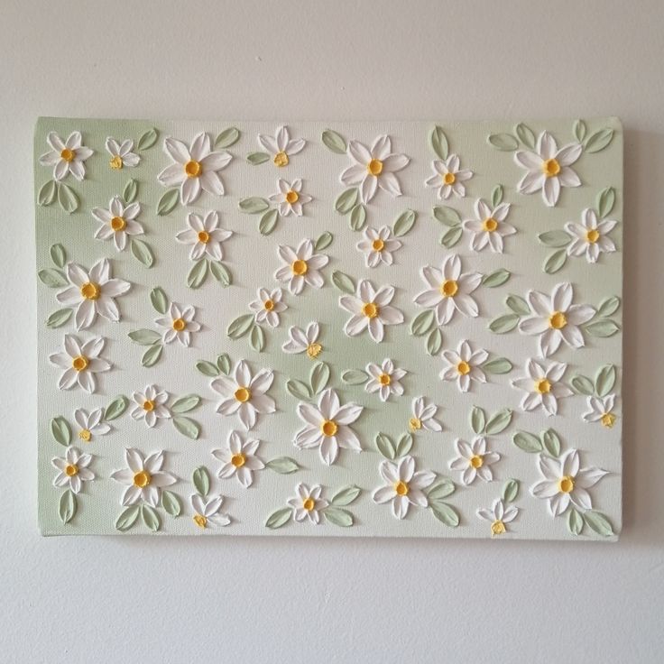 a white and green flowered wall hanging on the side of a wall in a room