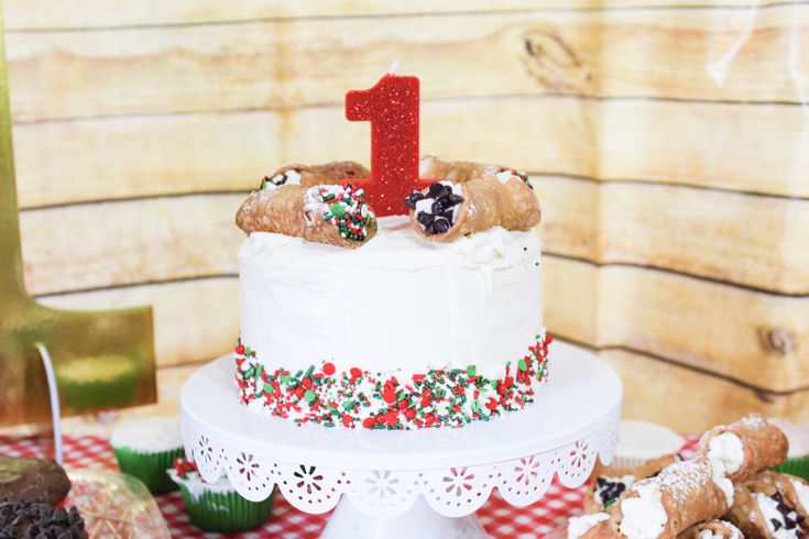 a white cake sitting on top of a table next to cookies and other desserts