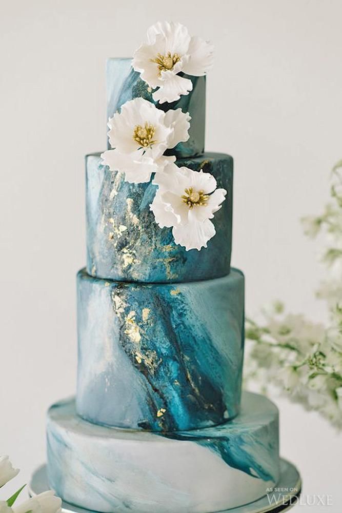 a three tiered blue marble cake with white flowers on top