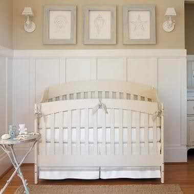 a white crib in a room with pictures on the wall