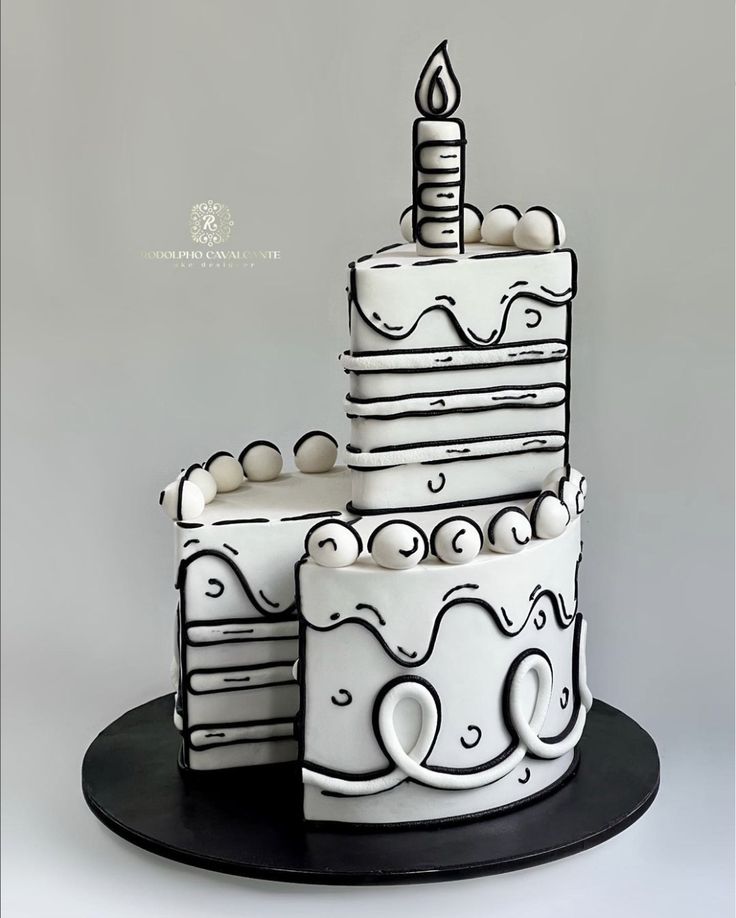 a three tiered cake is decorated with white frosting and black icing on a plate