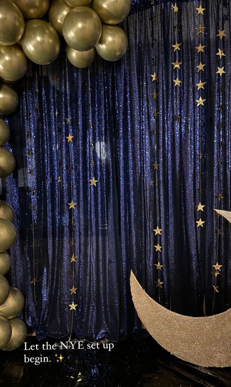 balloons and streamers are hanging from the ceiling in front of a blue curtain with gold stars