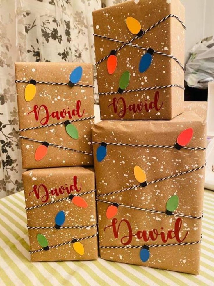 three presents wrapped in brown paper with string lights on them and the words david, david written