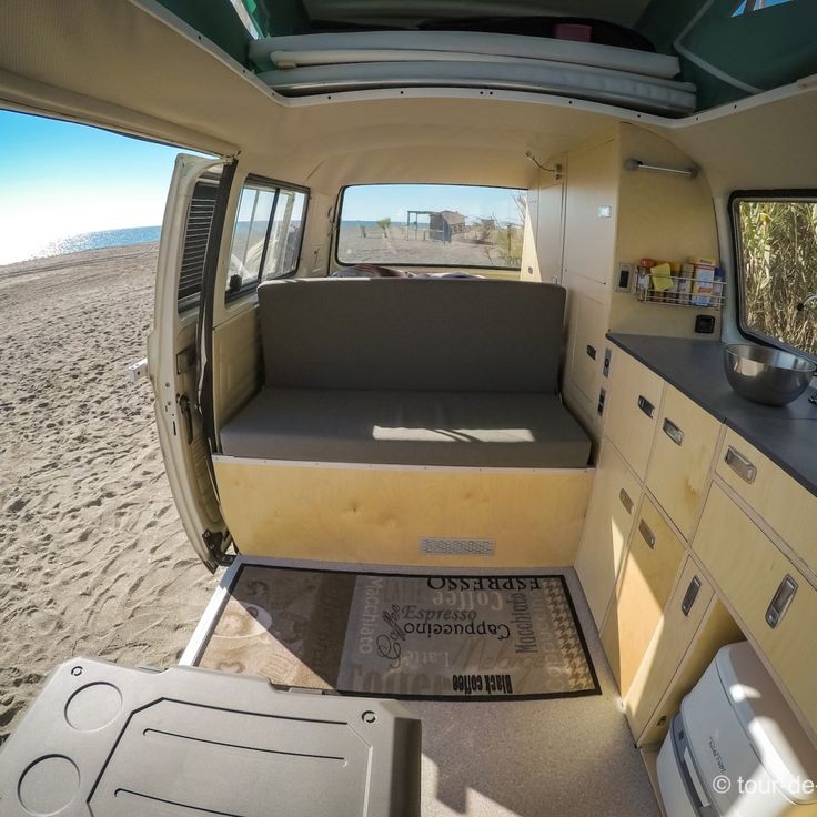 the interior of a van with its doors open and sand in the background, looking out onto the beach