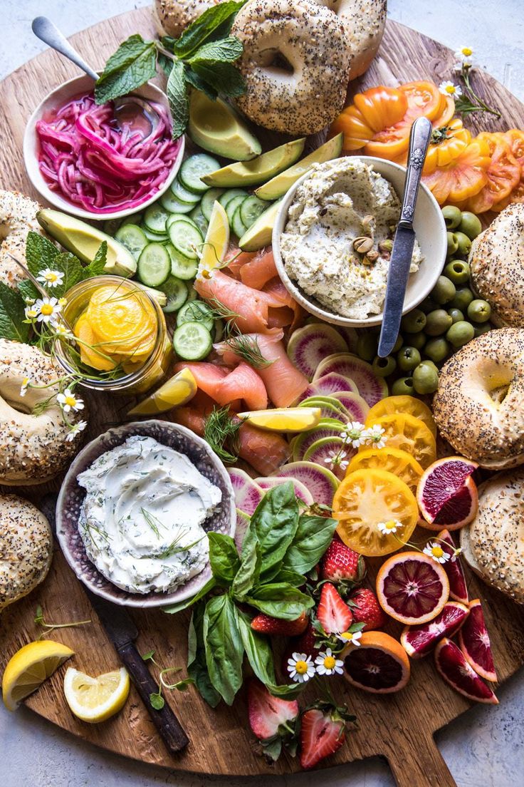 a platter with bagels, vegetables and dips