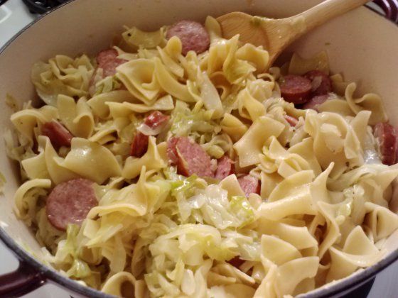 a pot filled with pasta and sausage on top of a stove