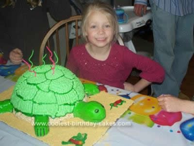 two children sitting at a table with a turtle cake