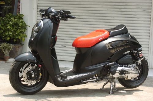 a black and red scooter parked in front of a garage