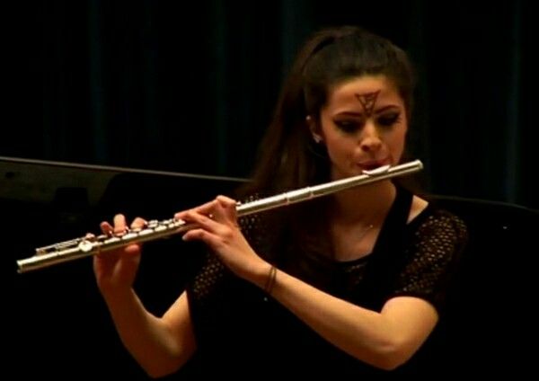 a woman is playing the flute on stage