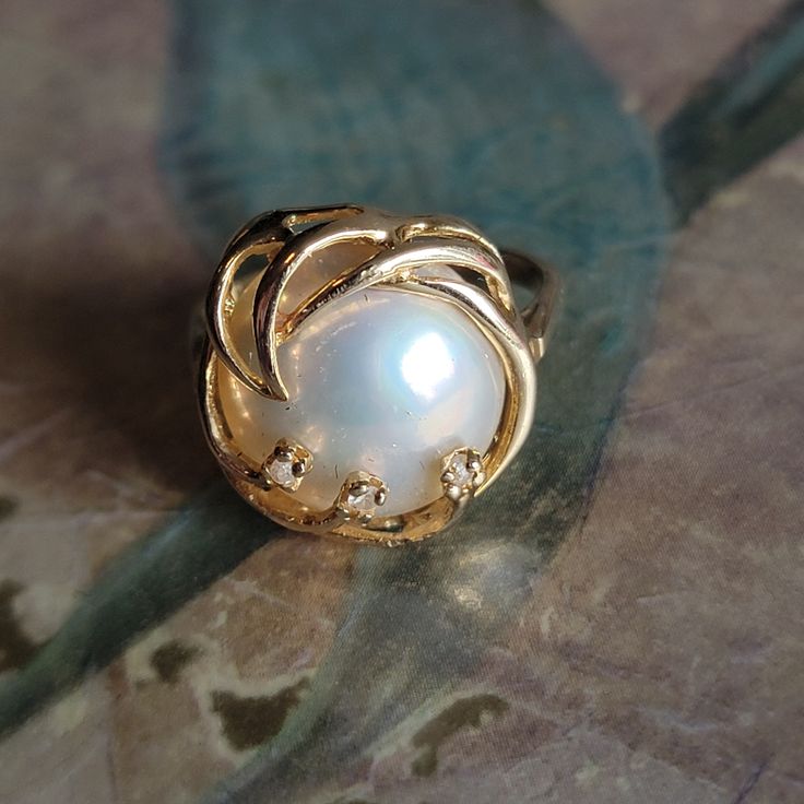 This is a vintage, 14 Karat gold, diamond and Mabe pearl ring. It has stamped 14 K and has tested positive for 14 karat gold.All sales are final.  This ring is a size 6 and can be sized. Please note, sizing is up to the buyer. I do not provide this service. If you have a wish list or are looking for something specific, please ask. I may have exactly what you are looking for.  As always please convo me with any questions or concerns regarding this item or with any international shipping questions. Unfortunately I do not accept returns or grant refunds. All shipping fees include handling fees. If you would like to combine shipping costs for more than one item, I would be happy to do so if you convo me before purchase.  Purchasing my item means you have read, understood and will abide by my p Heirloom White Gold Pearl Ring Stamped 14k, 14k Stamped Fine Jewelry Pearl Ring, Heirloom Pearl Ring With Diamond Accents, Heirloom Style Pearl Ring For Anniversary, Heirloom Pearl Anniversary Ring, 14k Stamped Fine Pearl Ring, Heirloom Style Pearl Ring In 14k Gold, Gold Heirloom Pearl Ring With Center Stone, Heirloom Pearl Ring With Prong Setting For Anniversary