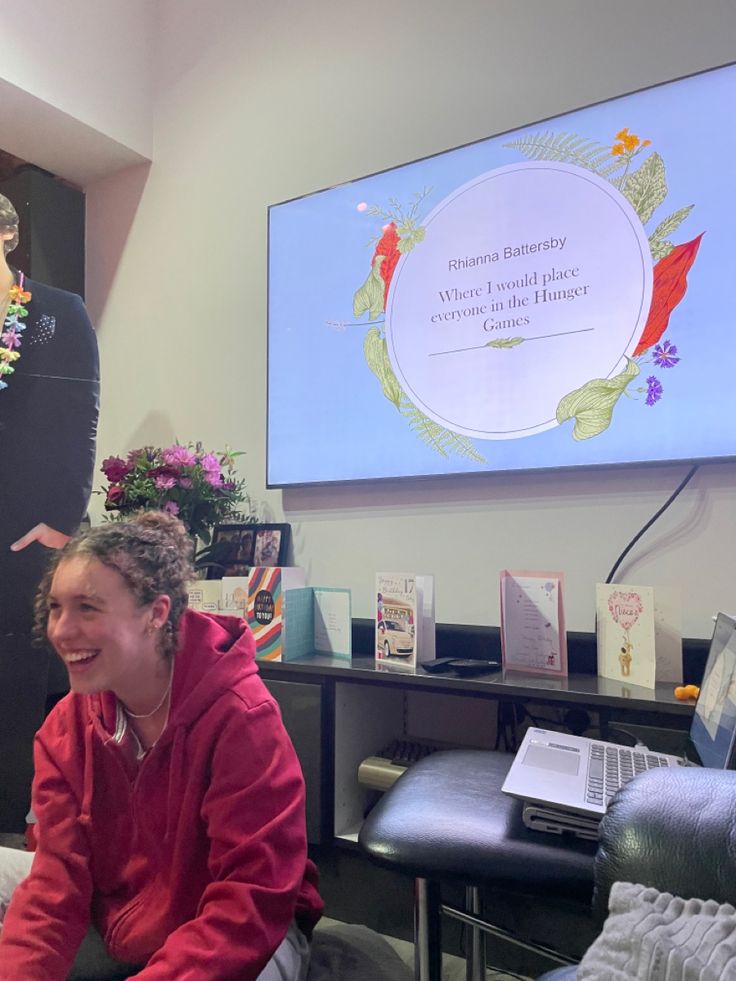 a woman sitting on the floor in front of a projector screen with flowers and cards