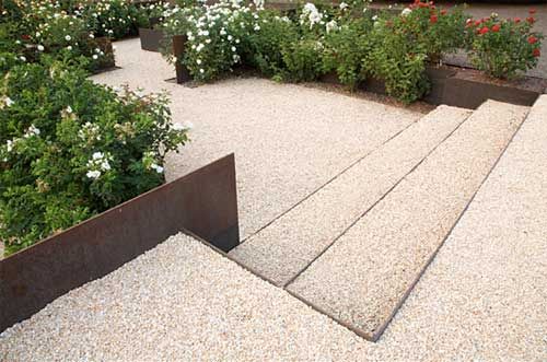 an outdoor garden area with various plants and flowers in the center, along with concrete steps leading up to it