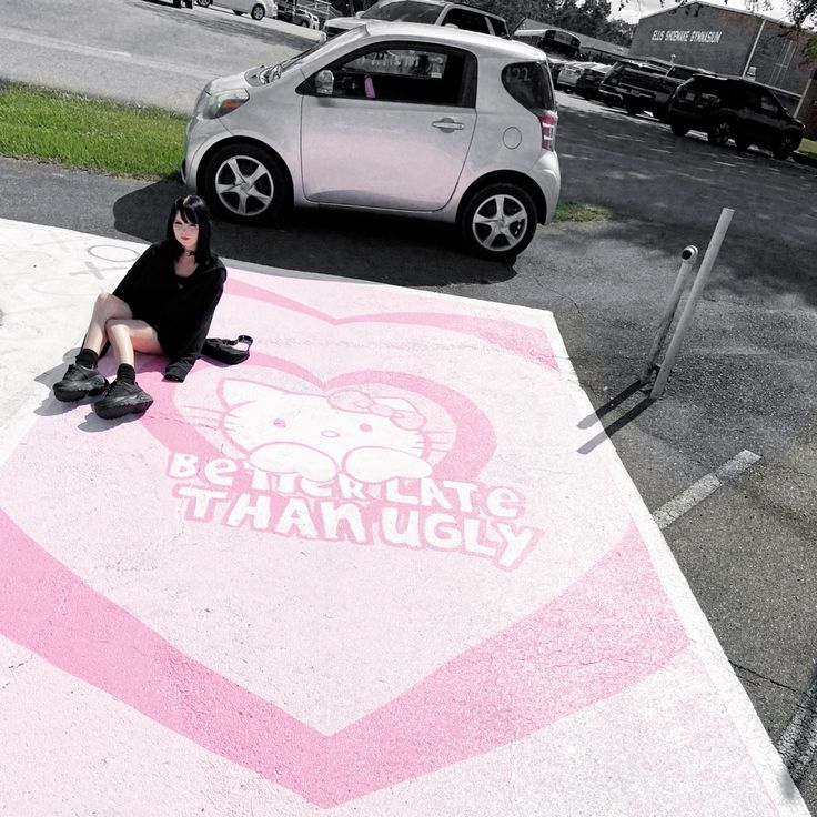 a person sitting on the ground in front of a pink heart painted with hello kitty