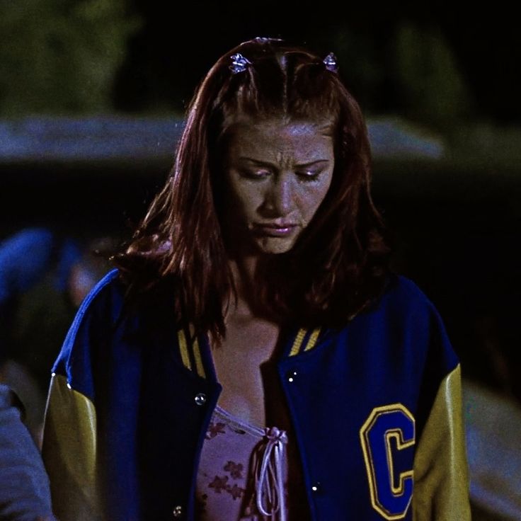 a woman with red hair wearing a blue and yellow jacket