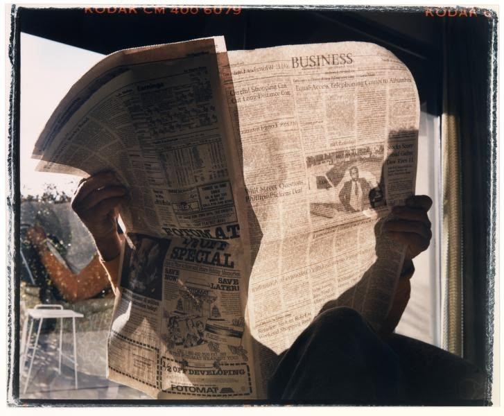 a person reading a newspaper while sitting in a chair