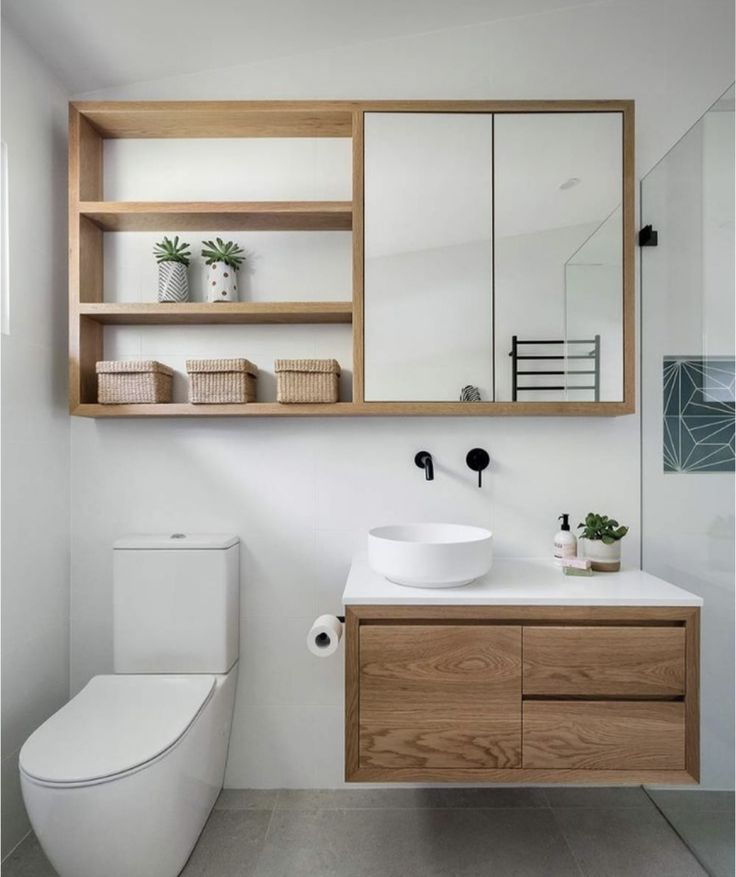 a bathroom with a toilet, sink and wooden cabinet in the corner on the wall