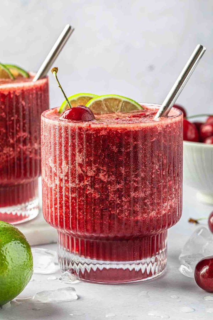 two glasses filled with cranberry margaritas and garnished with cherries