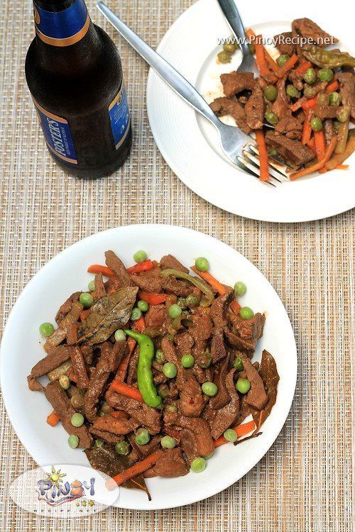 two plates filled with meat and vegetables next to a bottle of beer on a table