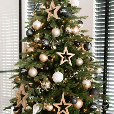 a christmas tree is decorated with black and gold baubs, stars, and ornaments