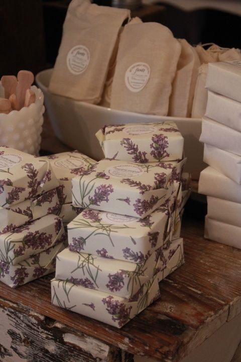 several packages of soap sitting on top of a wooden table in front of other items