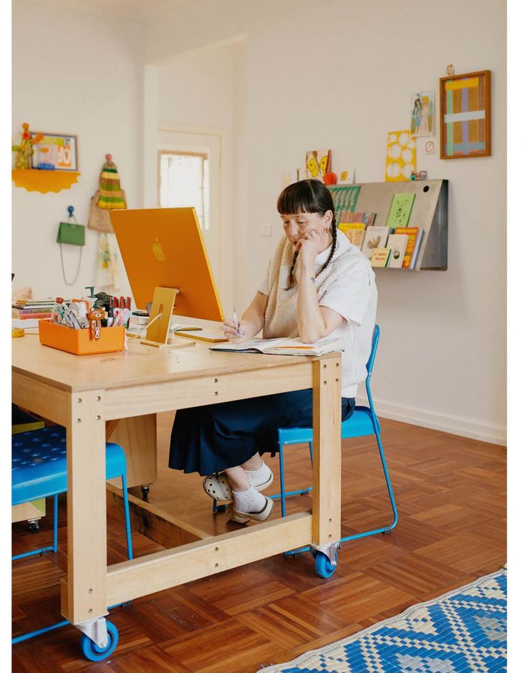 a woman sitting at a table with a laptop on her lap and talking on the phone