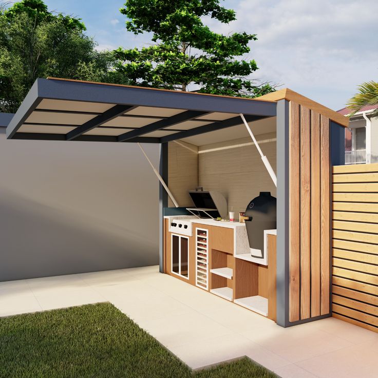 an outdoor kitchen is built into the side of a fenced in area with grass and trees