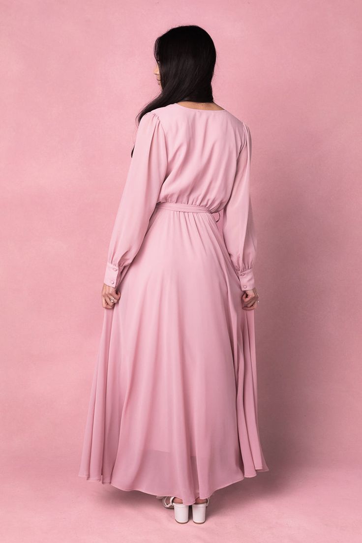 Say hello to the Andie Dress in Blush. Dare we say she's the perfect mother of the bride dress?! She's an amazing blend of style and comfort. This maxi dress features a soft pink base with a flattering faux wrap bodice and elastic waist for a flattering fit. The functional pockets and lined bodice and skirt add practicality, while the fabric's stretch makes it suitable for both maternity and nursing. With a v neckline and long, unlined sleeves, this dress is versatile AND chic. Pink V-neck Midi Dress For Wedding Guest, Elegant Pink Asymmetrical Maxi Dress, Feminine Floor-length Midi Dress For Wedding Guest, Feminine Long Midi Dress For Wedding Guest, Elegant Pink V-neck Wrap Dress, Pink Flowy Modest Maxi Dress, Chic Flowy Mauve Dress, Spring Pink V-neck Gown, Pink V-neck Spring Gown