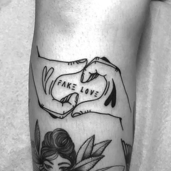 a woman's leg with a tattoo that says fake love and leaves on it