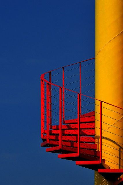 a red staircase going up to the top of a yellow tower