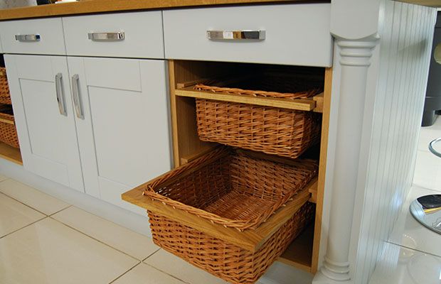 two wicker baskets sit in the bottom drawer of a kitchen cabinet