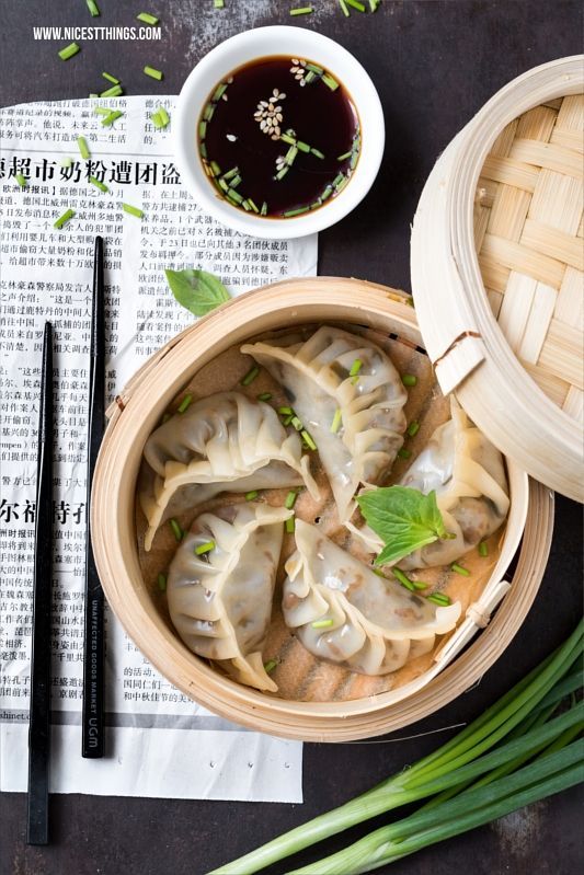 dumplings and chopsticks sit on a newspaper next to two bowls of soup