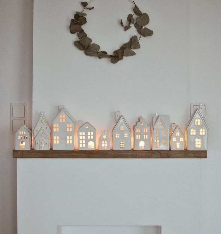 a fireplace mantle with lit candles in the shape of houses