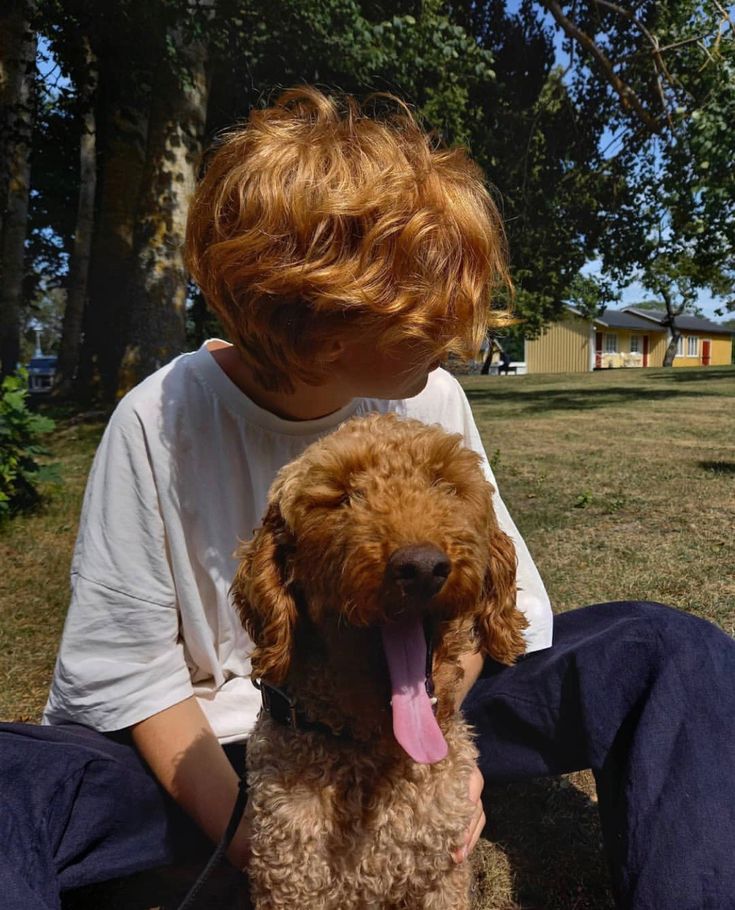 a young boy sitting on the ground with his dog, who is panting at him