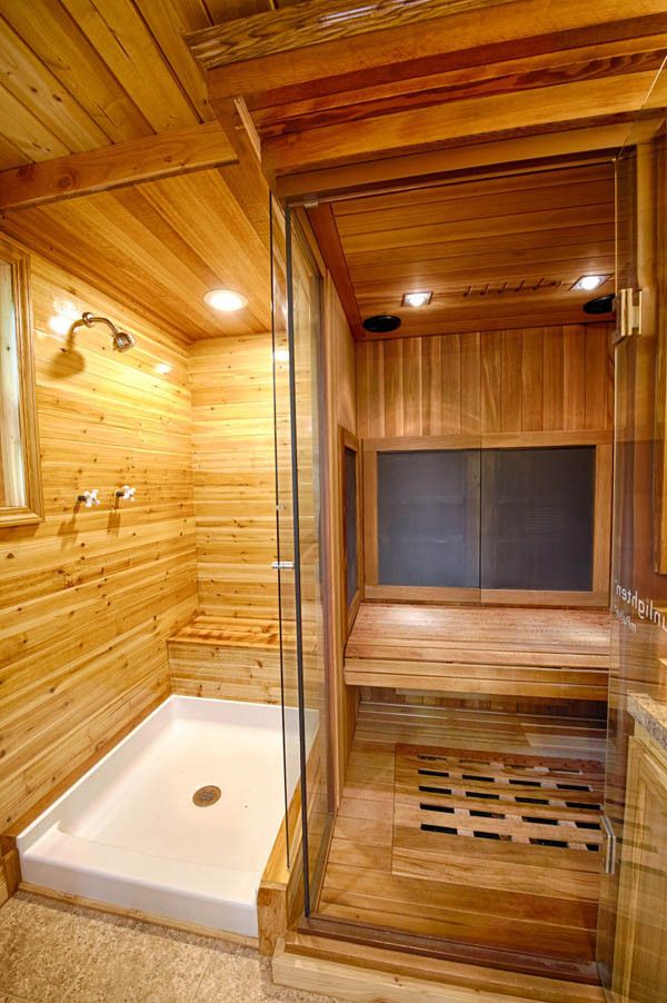 a sauna in a wooden room with glass doors and lights on the ceiling is shown