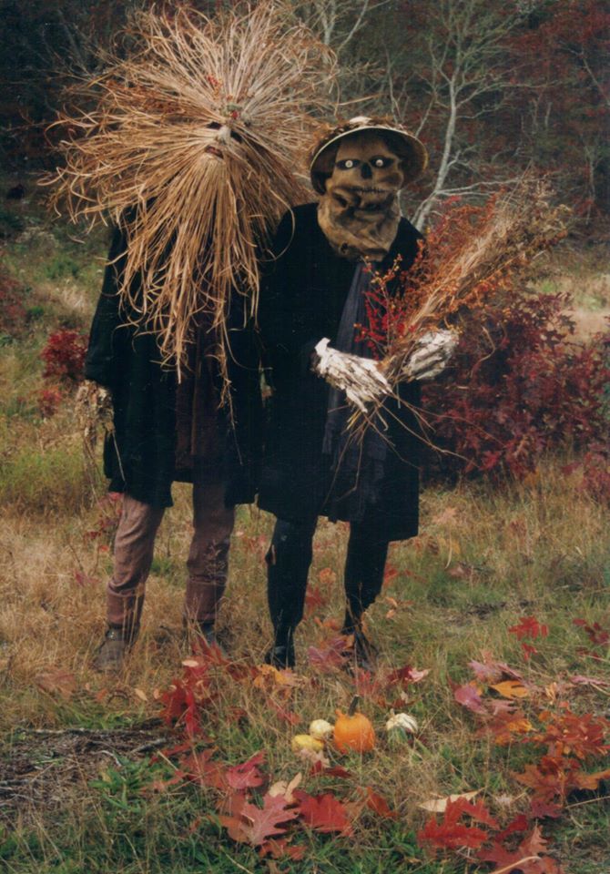 two scarecrows in the woods with their heads turned to look like they are holding hay