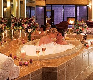 a man and woman in a jacuzzi tub surrounded by candles