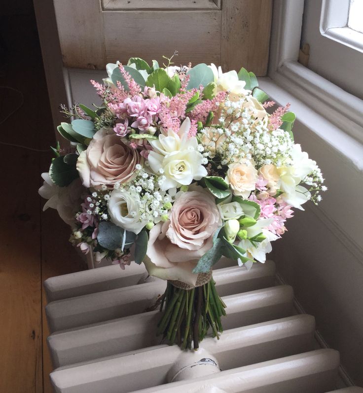 a bouquet of flowers sitting on top of a set of stairs next to a window