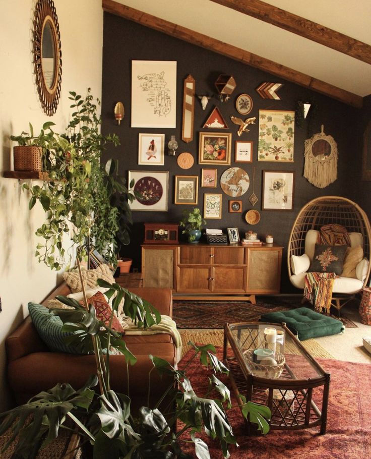 a living room filled with lots of plants and pictures on the wall next to a couch