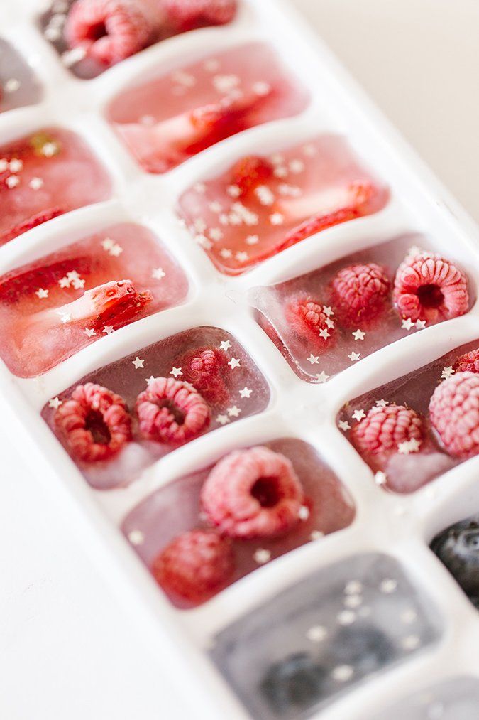 raspberries and other fruits are in an ice tray