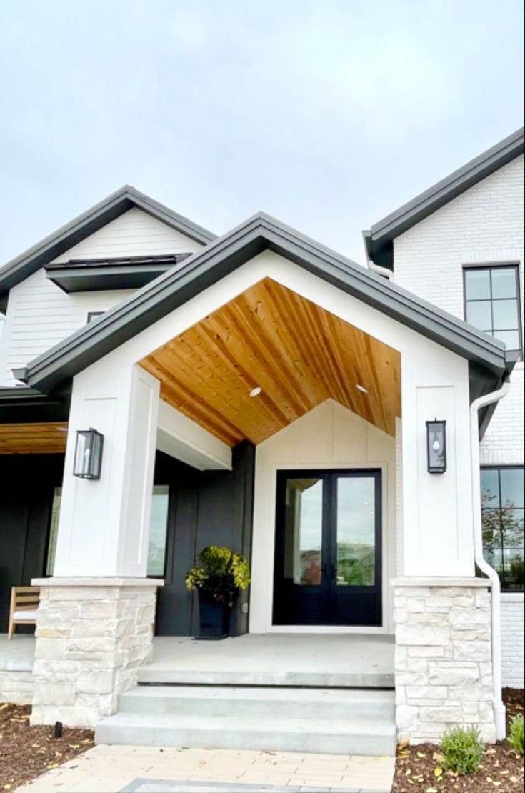 the front entrance to a house with white walls and wood roofing on it's sides