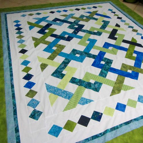 a green and blue quilt sitting on top of a floor