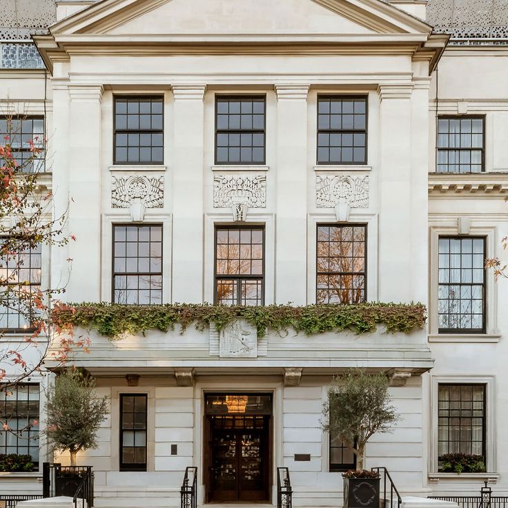 a large white building with lots of windows and plants on the front window sill