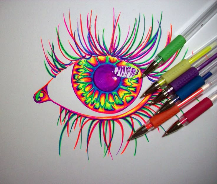 some markers and pens are next to a drawing of an eye with colorful feathers on it