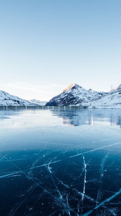 an ice covered lake with mountains in the background