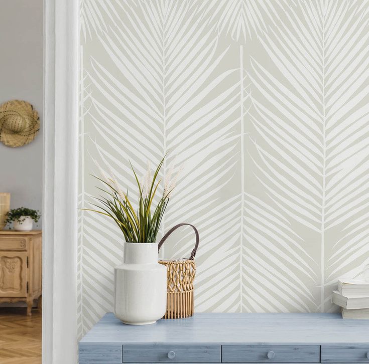 a blue bench in front of a white wall with palm leaf stencils on it