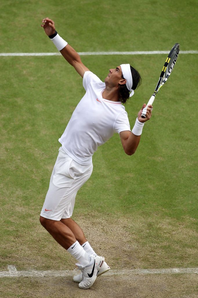 a man holding a tennis racquet on top of a tennis court with his hand in the air