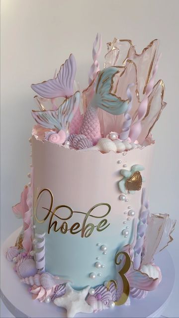 there is a pink and blue cake with mermaid decorations on it