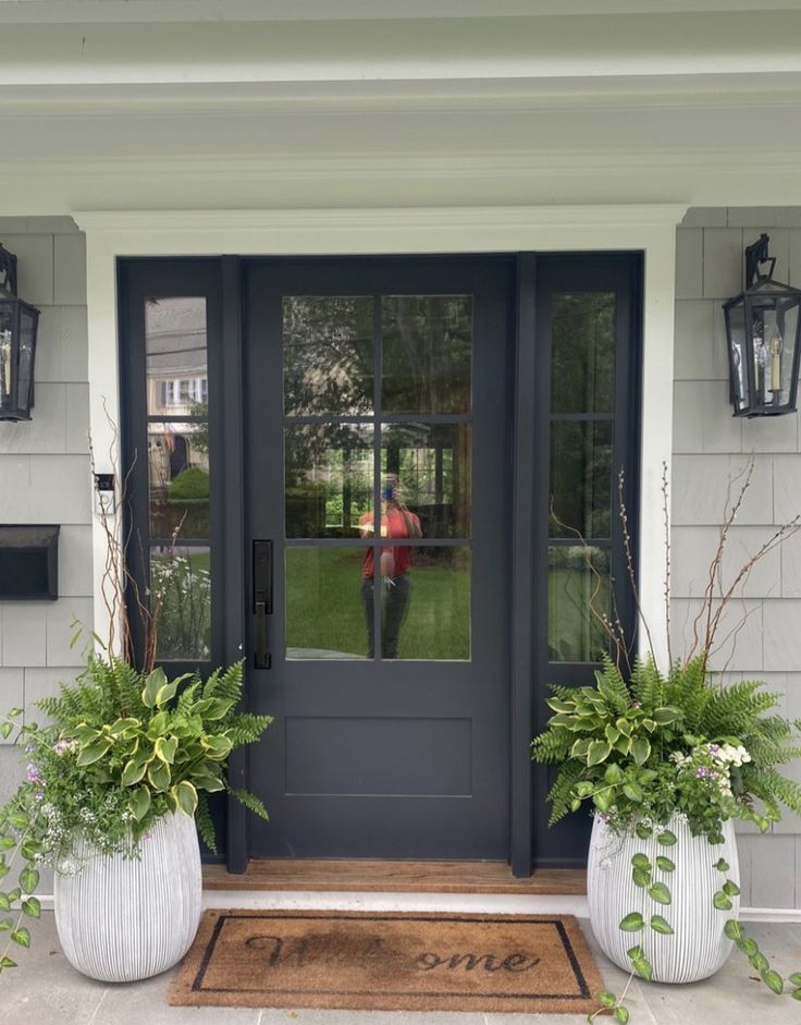 two large white planters are on the front steps of a house with black doors