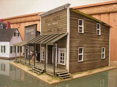 there is a miniature house on display in front of the water's edge with people standing outside